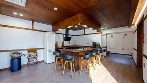 A modern kitchen with a central island, bar stools, a refrigerator, and a sink. - GurYong RyoKan (Pohang)