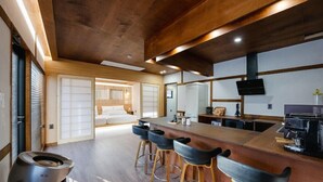 A modern kitchen with a wooden countertop, bar stools, and a built-in oven. - GurYong RyoKan (Pohang)