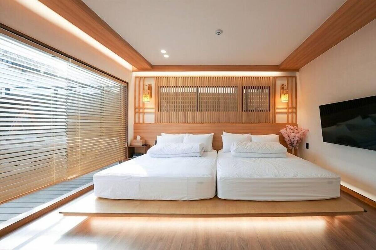 Ein modernes Hotelzimmer mit einem großen Bett, Holzvertäfelung und einem Fernseher an der Wand.