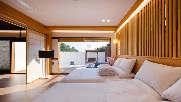 A hotel room with two beds, a TV, and a view of the outdoors. - GurYong RyoKan (Pohang)