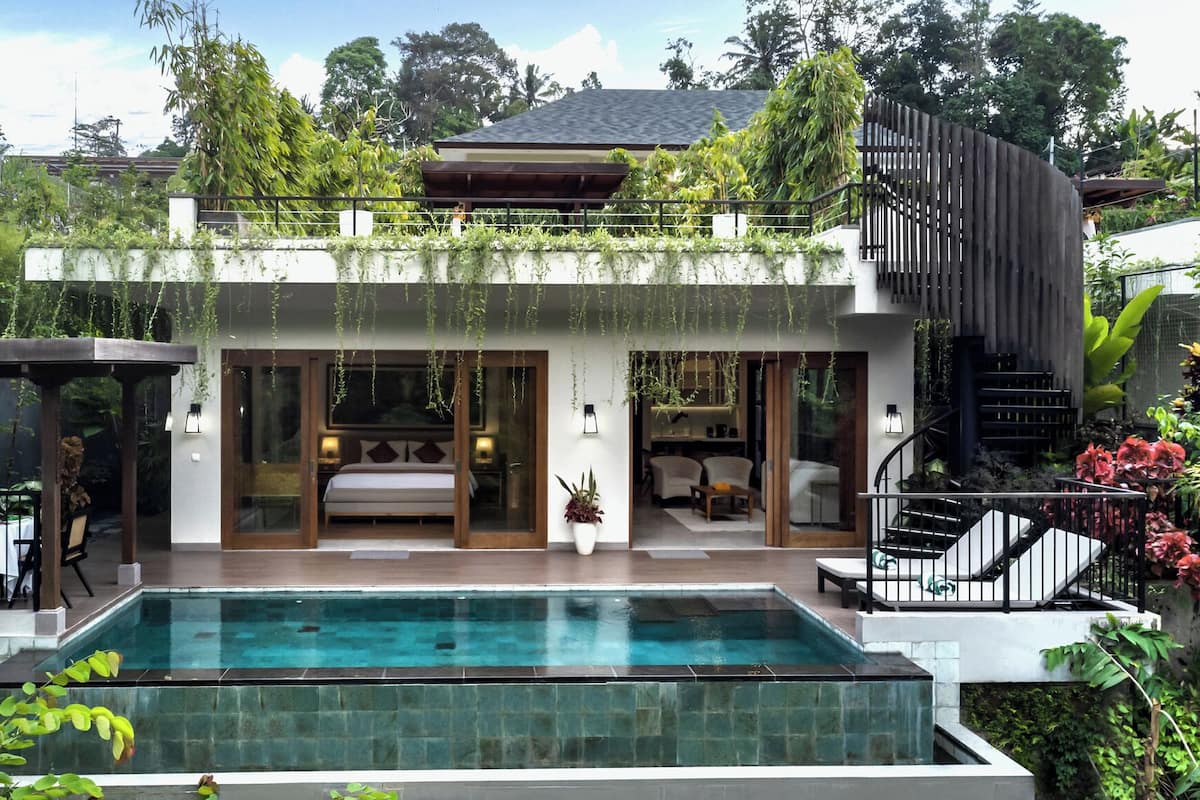 A modern house with a swimming pool, a covered patio, and a staircase leading to a second floor.