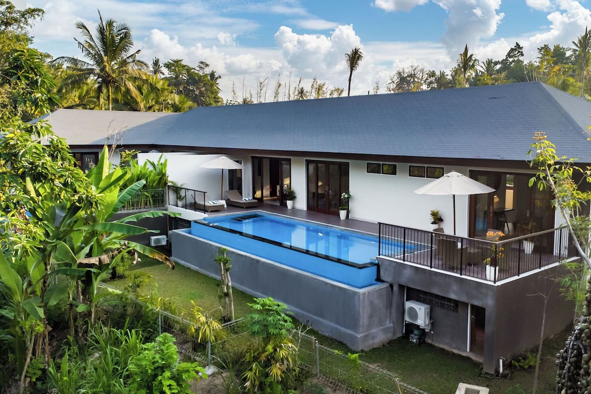 A modern house with a swimming pool, large windows, and a balcony.