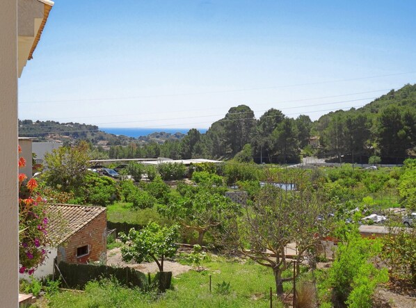 A residential area with a view of a hilly landscape, a clear sky, and a distant body of water.