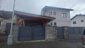 Edificio residencial con entrada porticada, muros de piedra y porche cubierto.