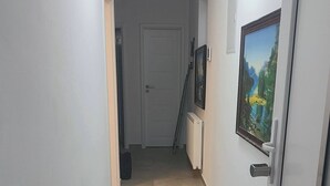 Un pasillo con suelo de baldosas, una puerta con cerradura electrónica y un cuadro en la pared.