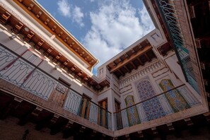 A multi-story building with balconies, ornate railings, and detailed architectural designs. - Asal Boutique Hotel (Bukhara)