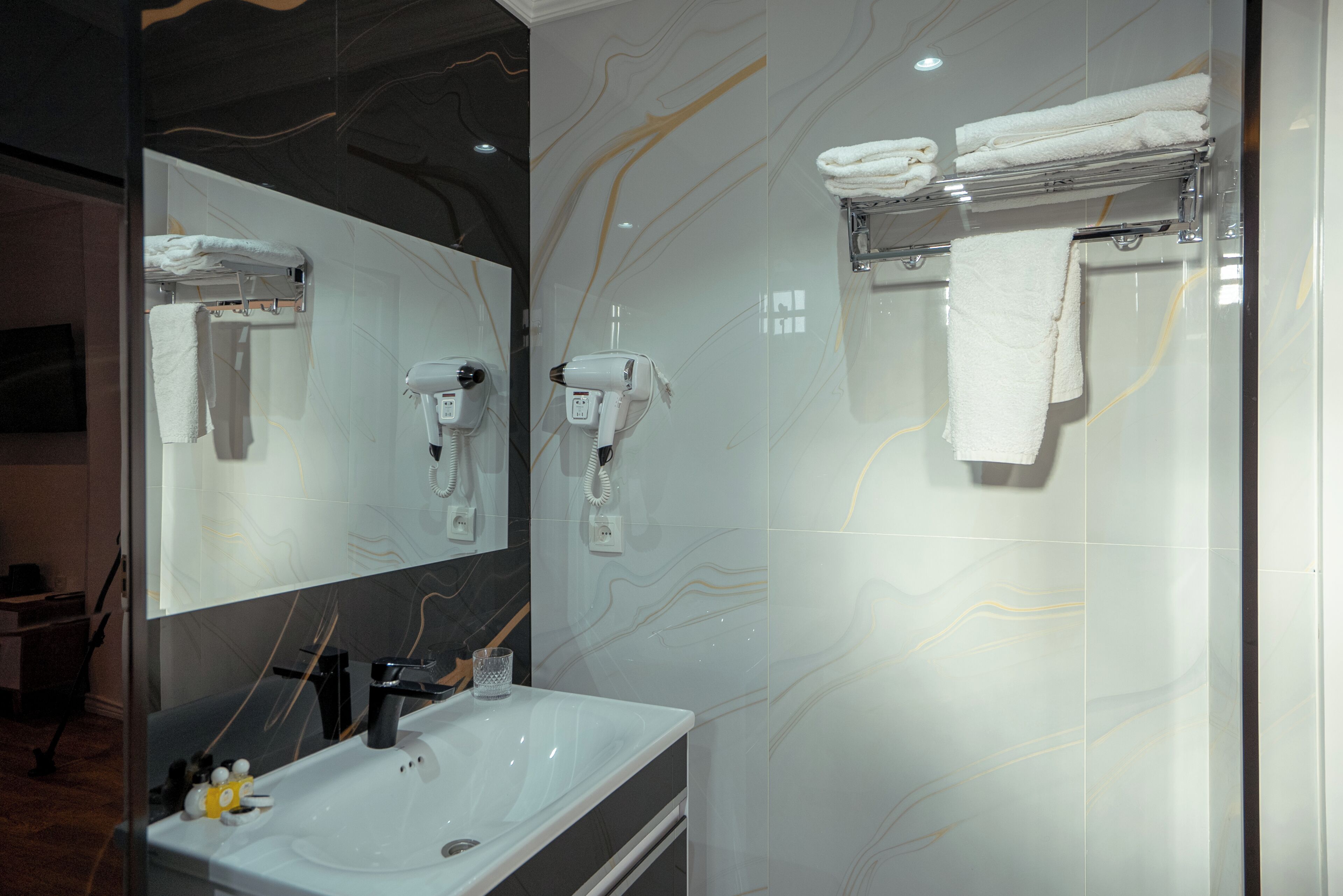 A modern bathroom with a large mirror, a sink, and a towel rack.