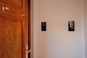 A hotel room with a wooden door, two black signs indicating room numbers 405 and 406, and a small window with a view.