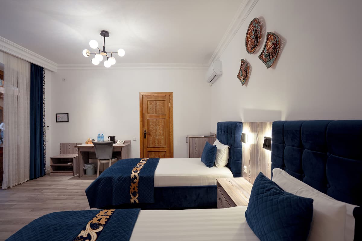 Quarto de hotel com duas camas, uma escrivaninha e um guarda-roupa.