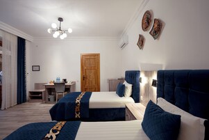 A hotel room with two beds, a desk, and a wardrobe.