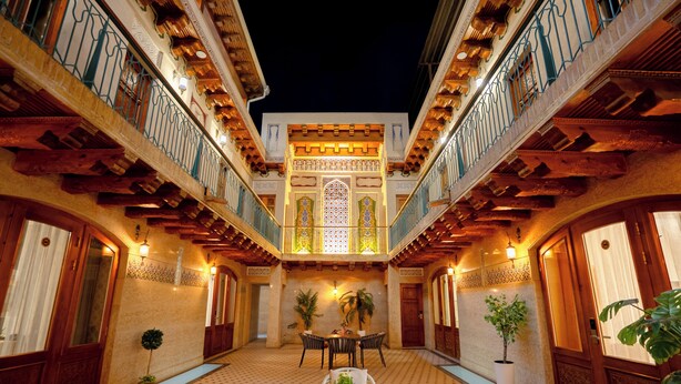 A courtyard with a central seating area, potted plants, and a decorative entrance. - Asal Boutique Hotel (Bukhara)