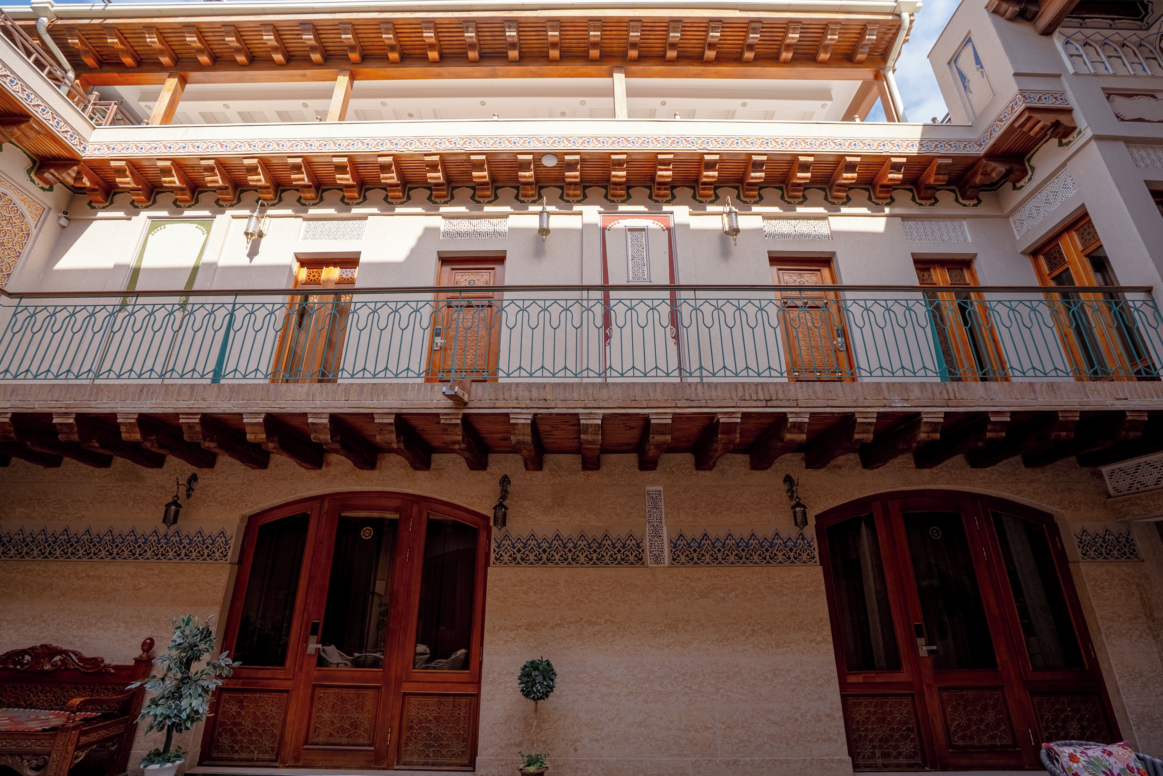 A traditional building with a wooden balcony, ornate doors, and patterned wall decorations.