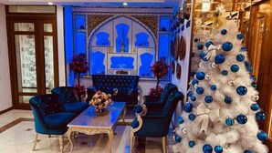 A dining area with a table and chairs, a decorative wall, and a Christmas tree. - Asal Boutique Hotel (Bukhara)