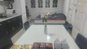 A dining area with a white table, black chairs, a vase with flowers, and a microwave on the counter. - Vu's Home - Apartment Deluxe 50m2 (Prague)