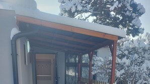 A snow-covered entrance with a wooden fence, a covered porch, and a building with a door. - Vu's Home - Apartment Deluxe 50m2 (Prague)
