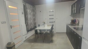A compact kitchen with a dining area, a small trash bin, and a ceiling light fixture. - Vu's Home - Apartment Deluxe 50m2 (Prague)