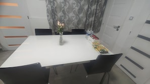A white table with black chairs, a vase with flowers, and a tray with snacks and water bottles.