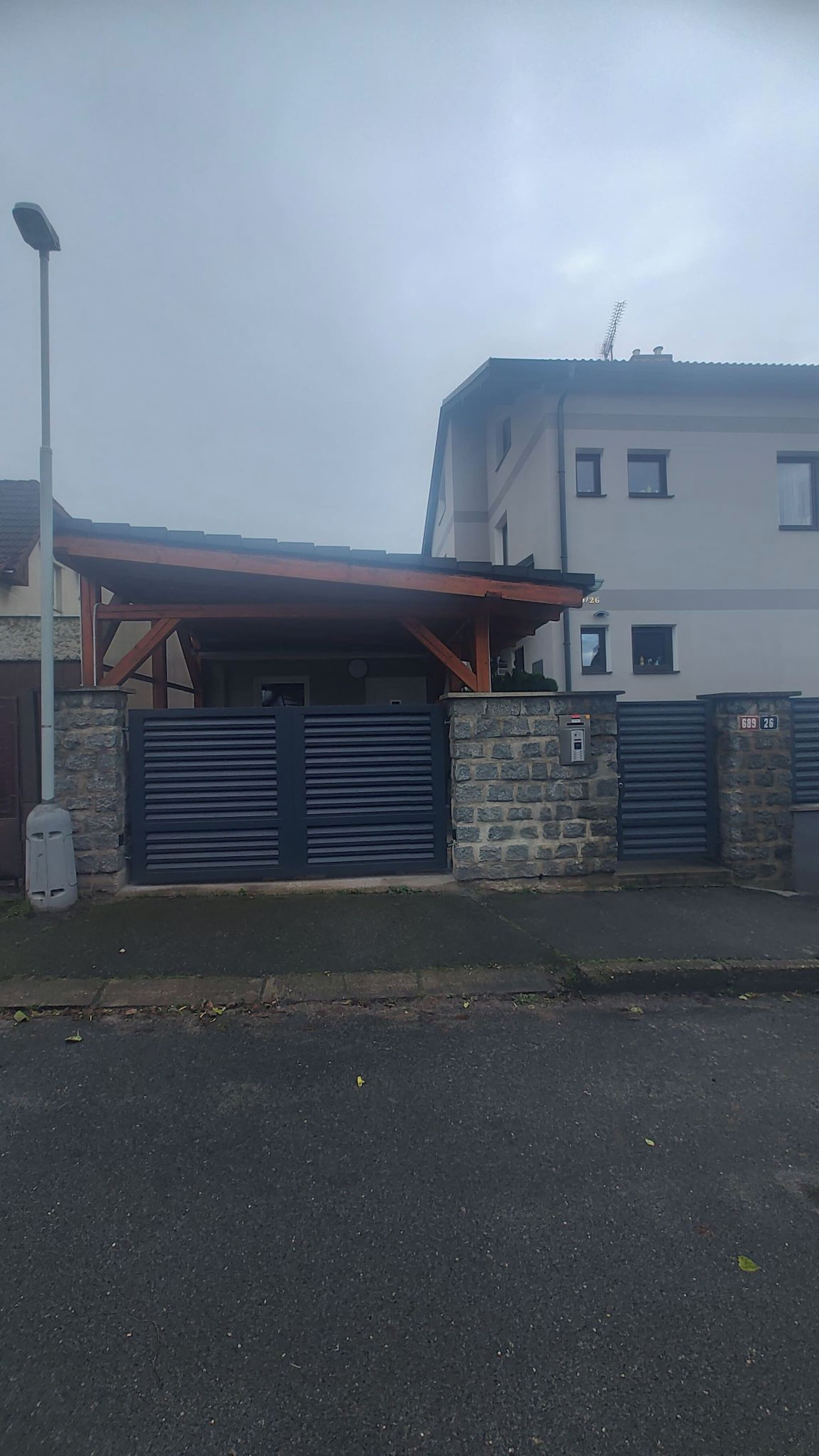 A building with a gated entrance, a covered parking area, and a stone wall.
