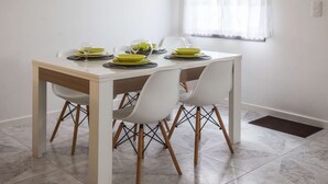 A dining table with four white chairs, a white tablecloth, and green plates and glasses. - Atlantic City - Marina (Ponta Delgada)