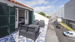 A rooftop terrace with outdoor seating, a bed, and a view of the street. - Atlantic City - Marina (Ponta Delgada)