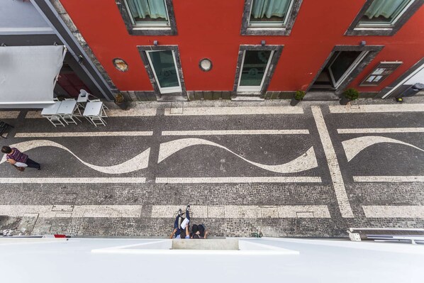 A street view with a red building, a pedestrian crossing, and a person sitting on a bench.