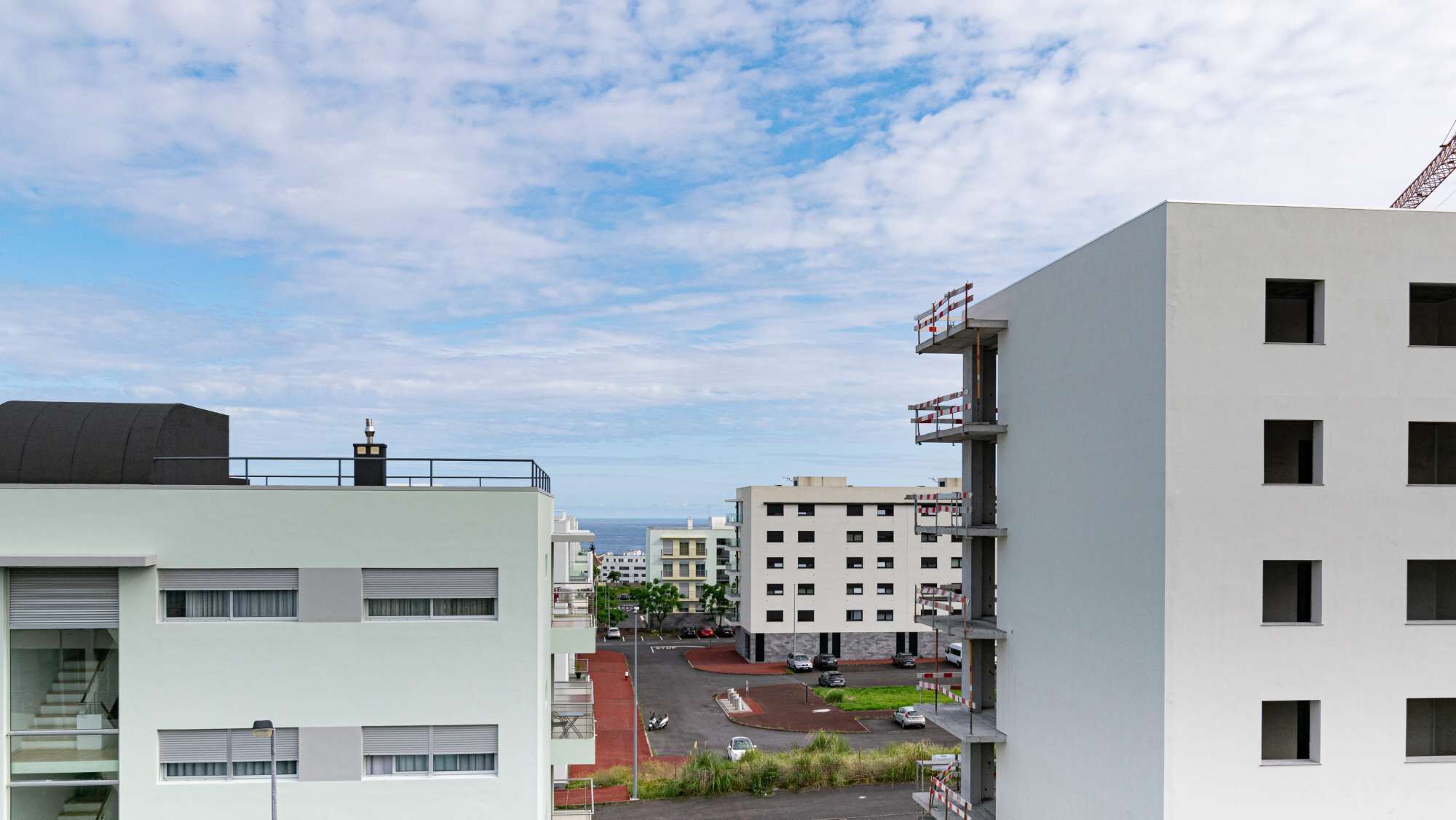 A modern urban building with multiple floors, large windows, and a rooftop with a chimney.