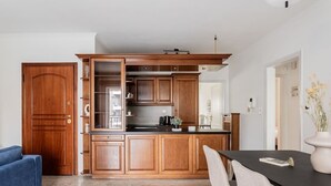 Una cocina moderna con armarios de madera, encimera negra y comedor con mesa y sillas.
