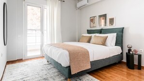 Um quarto com cama, janela com cortinas, ar-condicionado fixado na parede e quadros decorativos.