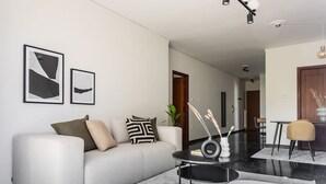 Un salon moderne avec un canapé, une table basse et des œuvres d’art encadrées accrochées au mur.