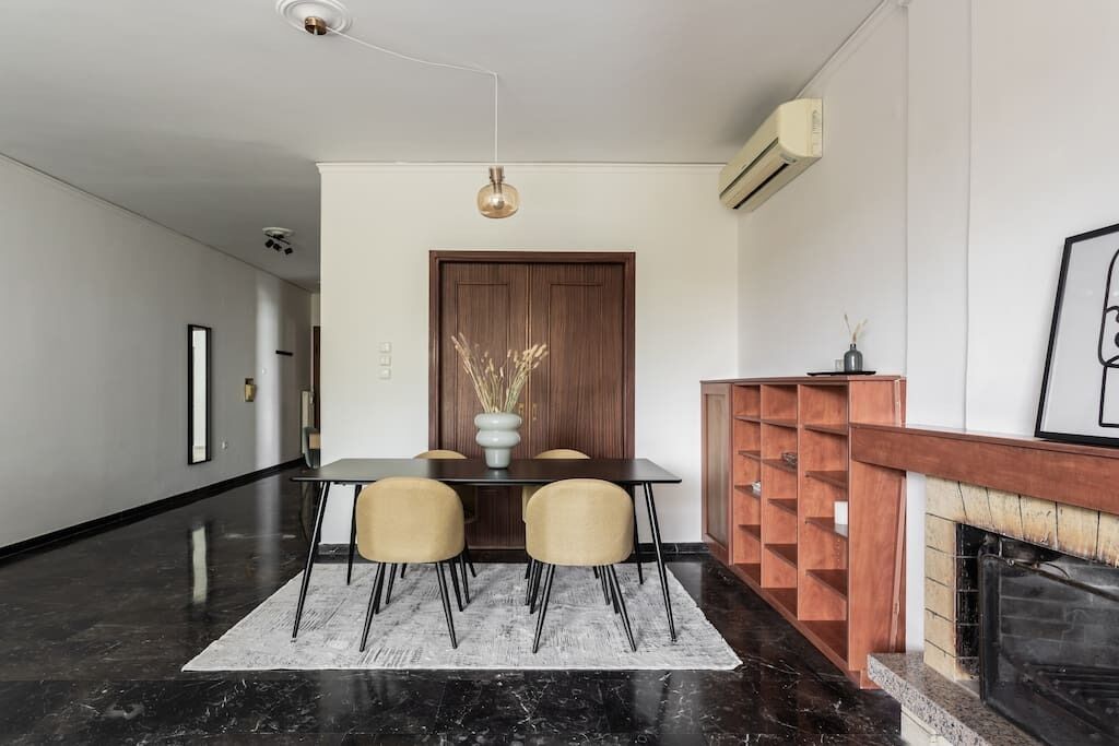 A modern dining area with a black marble floor, a wooden door, and a fireplace.