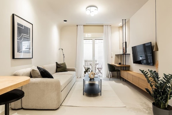Relax in this stylish living room with a comfortable sofa, flat-screen TV, and dining table.