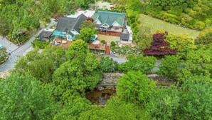 Vista aérea de una propiedad residencial con varios edificios, un puente de piedra y abundante vegetación.