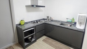 Una cocina moderna con estufa integrada, microondas y horno, un lavamanos de acero inoxidable y una cafetera.