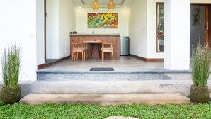 A dining area with a table and chairs, a kitchen counter, and a colorful painting above the counter.