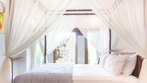 A bedroom with a bed, white bedding, and sheer curtains.