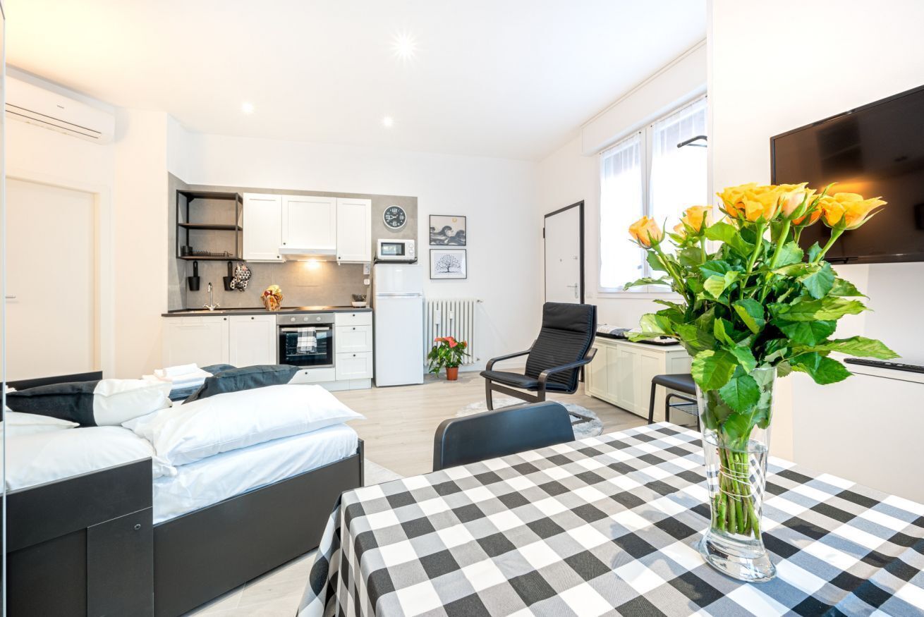 A compact living space with a bed, a dining table, a kitchen area, and a TV.