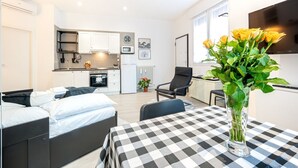 Um espaço compacto com cama, mesa de jantar, cozinha e televisão.