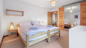 A bedroom with a wooden bed, a bedside table with a lamp, a mirror, and a wardrobe. - Valaisia 55B - 5 pers - plein centre (Haute-Nendaz)