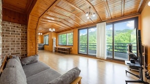 A spacious room with a wooden ceiling, large windows, a sofa, and a TV. - Heaven Valley A (Namyangju)