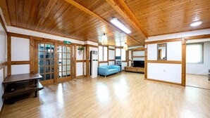 A room with wooden flooring, a blue sofa, a TV, and a wooden ceiling. - Heaven Valley A (Namyangju)