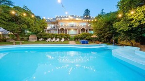 Una piscina con sillones de descanso y un edificio grande al fondo.