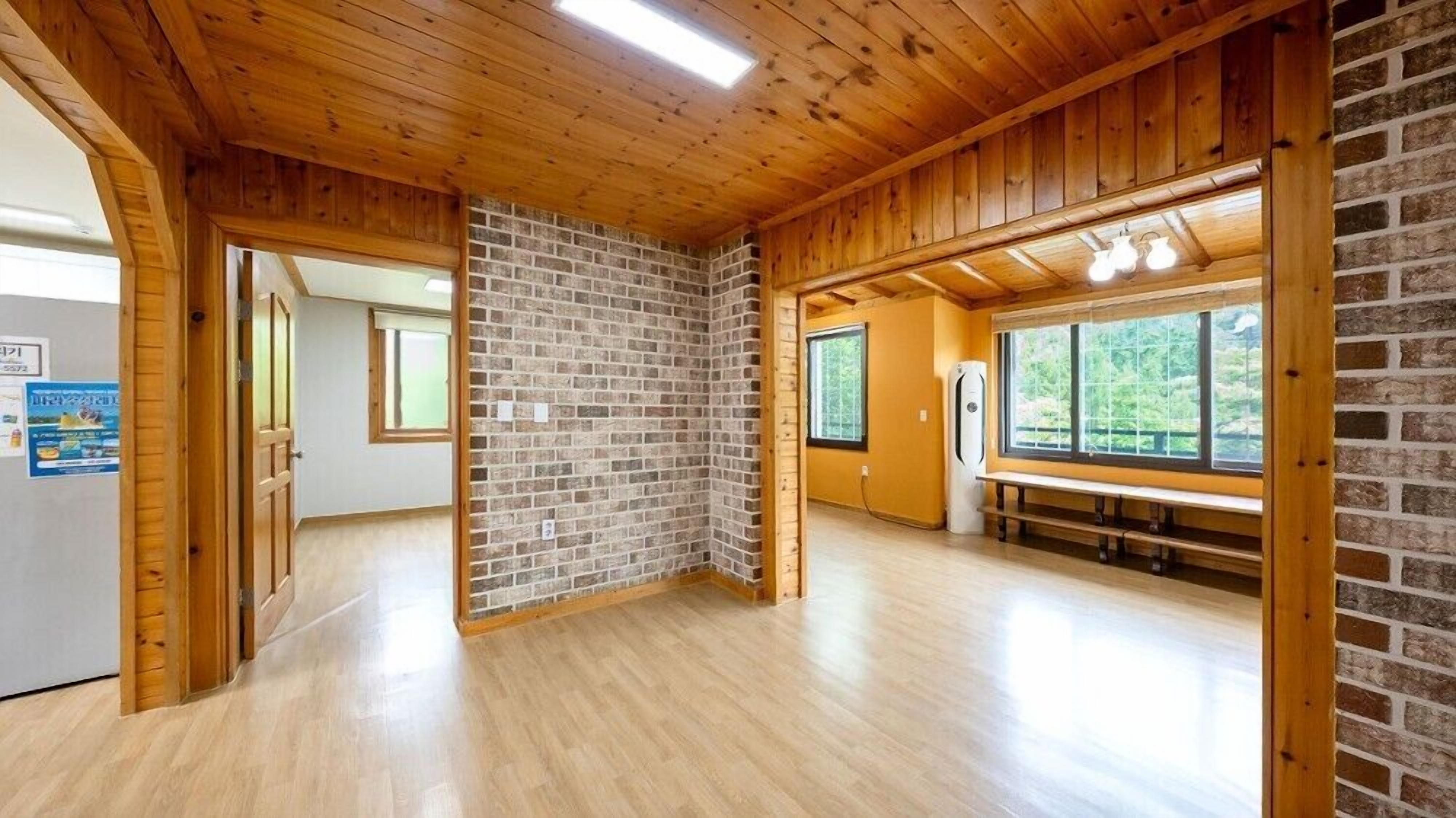 Una habitación con pisos de madera, paredes de ladrillo y un ventanal grande.