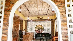 A reception area with a brick wall, a large decorative wheel, and a reception desk. - Sokchea Kampot Hotel (Kampot)