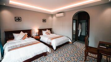 A hotel room with two beds, a tiled floor, a wooden headboard, a nightstand, and a mirror.