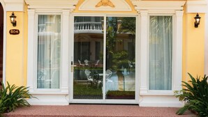 A yellow building with a number '504' on the wall, large glass doors, and a balcony with chairs. - Sokchea Kampot Hotel (Kampot)