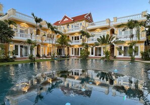Un hotel grande de varios pisos con un patio central que incluye una piscina reflectante.