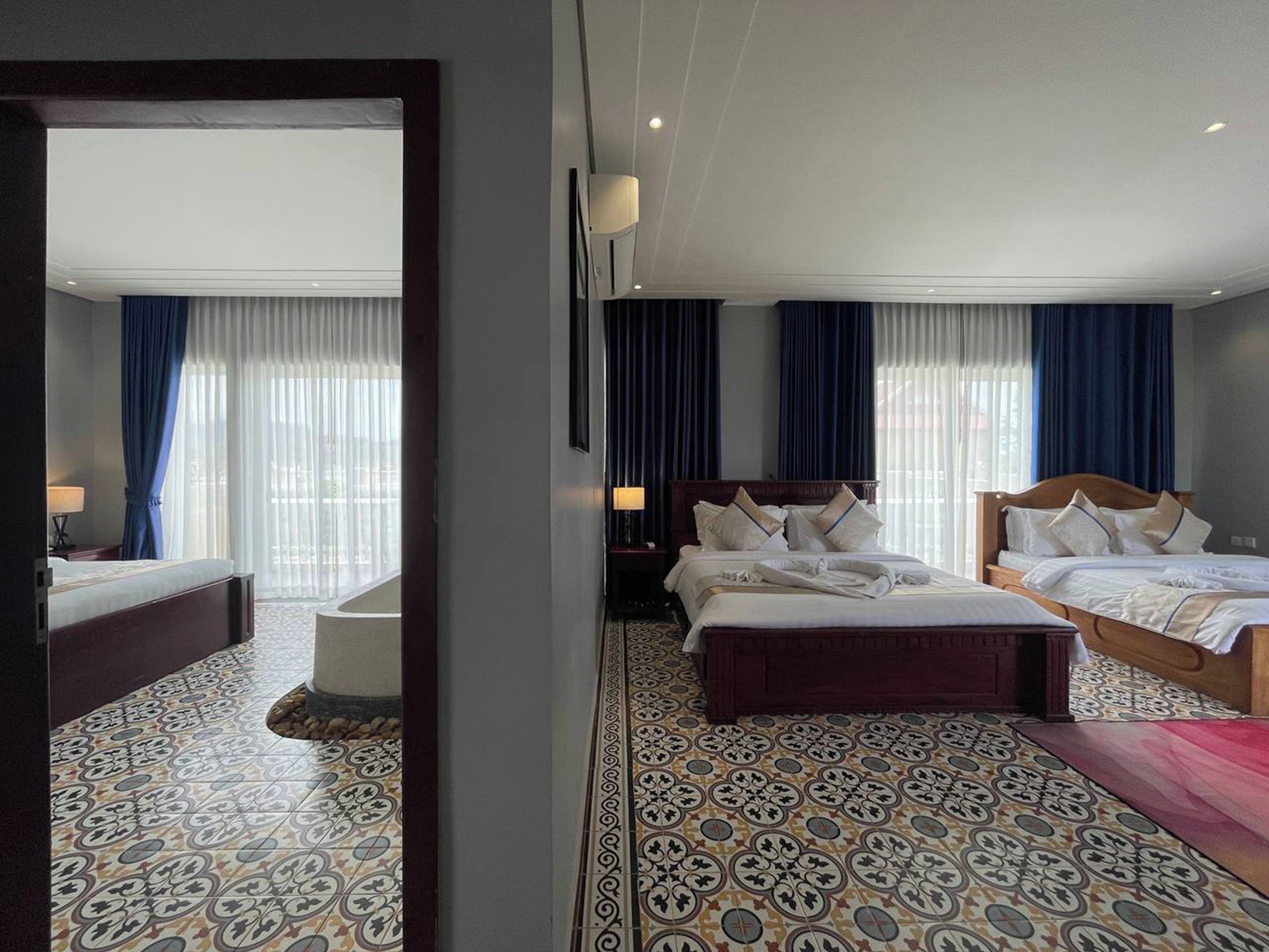 A hotel room with two beds, a sitting area, and a large window with curtains.