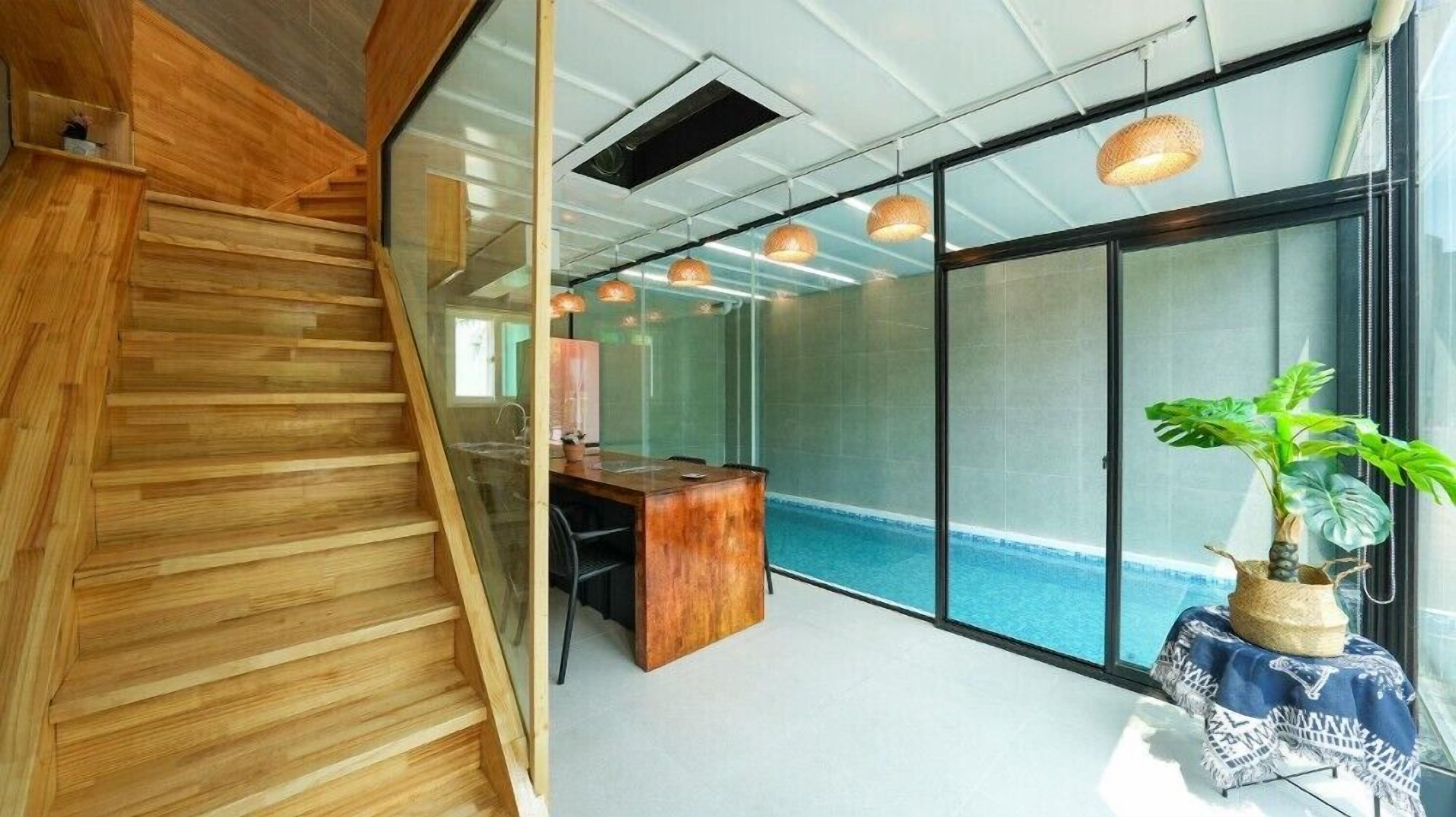 Een modern kantoor met een houten trap, een receptiebalie en een grote glazen wand met uitzicht op een zwembad.