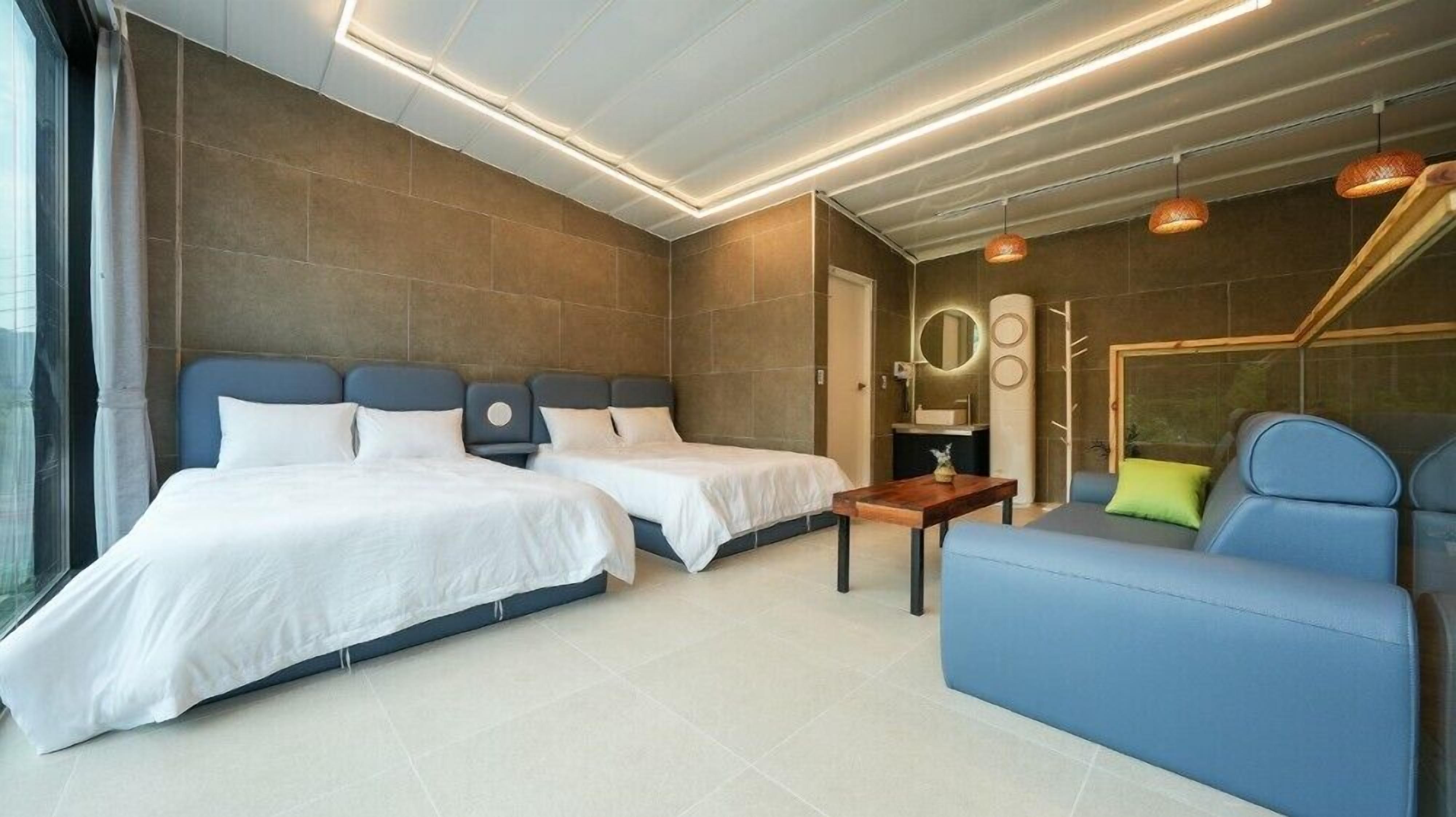 Una habitación de hotel moderna con dos camas, un sofá y una pequeña mesa.