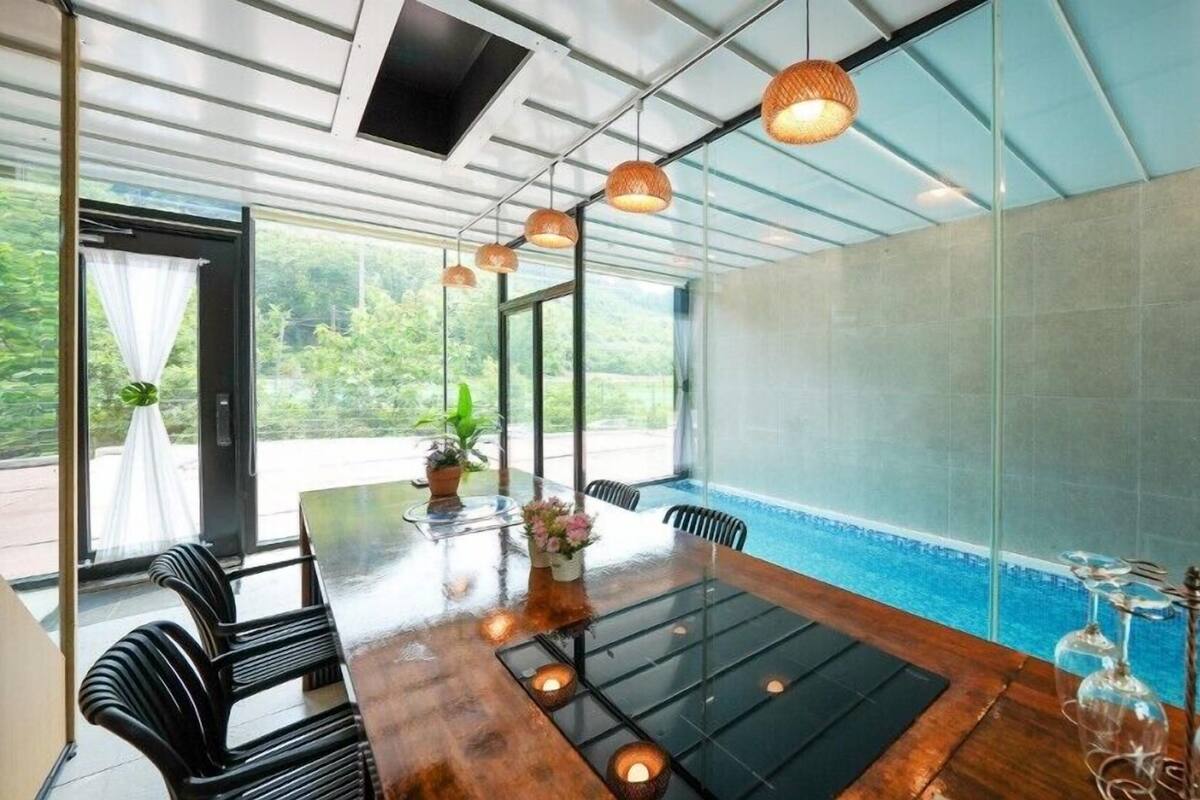 A spacious dining area with a large table, chairs, and hanging pendant lights.